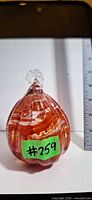 Front view of red and clear swirl glass paperweight with stem, size reference with ruler