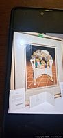Framed print showing cats and stuffed animals on wicker rocker with COA cards