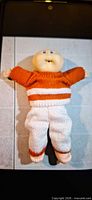 Full view of Cabbage Patch doll wearing knitted outfit