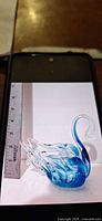 Full view of glass swan beside ruler for scale