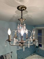 Chandelier lit showing bulbs, crystals, canopy, chain