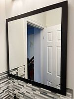 Mirror front view showing brown frame and reflected doorway