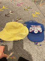Blue Dodgers trucker cap and yellow bucket hat on carpet
