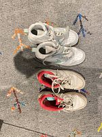 Both pairs of sneakers side by side on floor