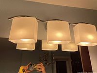 Front view of one vanity fixture lit, showing chrome bar and frosted square glass shades