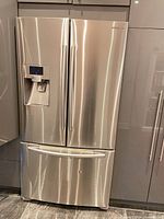 Front view of stainless steel Samsung French door refrigerator with freezer drawer and dispenser