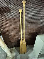 Front view of two wooden canoe paddles leaning upright