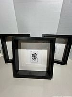 Three black shadow-box frames with matted playing card illustrations