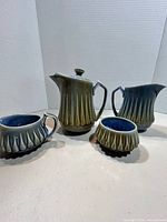 Full view of all four porcelain pieces showing fluted bodies, gradient glaze, and blue interiors