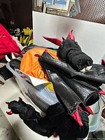 Bin showing dragon costume with horns and claws on top of other costumes