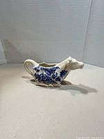 Right side view of ceramic cow creamer showing blue floral transfer pattern and overall shape