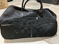 Front view of the black Coach signature jacquard duffel bag showing overall shape, exterior pocket and wear