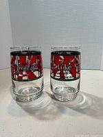 Two branded stained-glass Coca-Cola tumblers on white background
