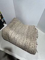 Folded braided gray-beige woven rug on table
