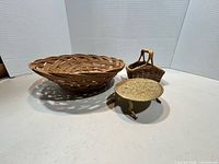 Three items grouped: large rattan basket, small handled basket, metal pedestal