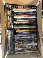 Open box showing stacks of about 40 DVD and Blu-ray cases with assorted visible titles