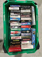 Overview of green tote containing entire lot of VHS tapes, spines visible for title verification