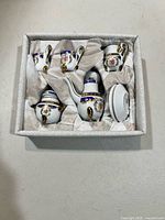 Boxed miniature porcelain tea set pieces in fitted satin-lined case