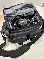 Open Nikon camera bag showing interior, lens cap, cords