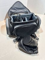 Optex camera bag open showing compartments, Canon lens and pouch visible