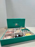Open teal display box showing compartments and teapots