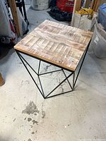Full view of table showing wood top and geometric metal base