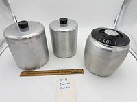 All three aluminum canisters with ruler for scale