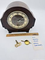 Front view of wooden mantle clock with key, pendulum and ruler for scale