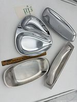 Group shot showing all four stainless dishes with ruler for scale