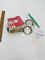 Stack of View-Master reels with sleeves beside ruler and note indicating 50+