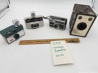 Group shot of all four vintage cameras with ruler for scale