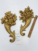 Pair of gold molded plastic cornucopia plaques with ruler and lot tag