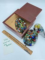 Wood box open with both mesh bags of marbles beside ruler