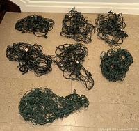Six bundled green net light sets laid out on floor