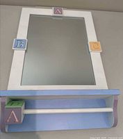Full view of mirror with shelf and alphabet blocks