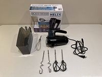 All components laid out: mixer, case, five attachments, retail box in background