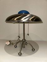 Full view of metal UFO table lamp showing dome, blue cap, pull chains, four-leg base
