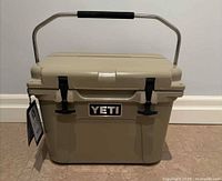 Front view of tan Yeti Roadie 20 cooler with metal handle raised and tag attached