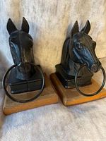 Front view of both cast-iron horse head bookends on wood bases