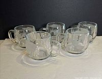 Five identical clear glass globe mugs displayed together