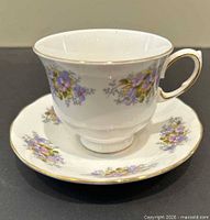 Teacup on saucer showing floral design and gold trim