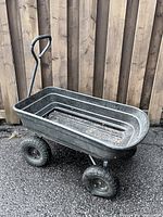 Side view of plastic-bed garden wagon with handle and four tires