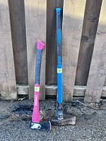 Two axes leaning against fence, full view