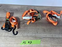 Three orange ratchet straps coiled on table