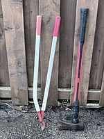 Splitting maul and edging shears standing against fence