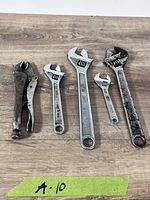 All five tools laid out on wood surface with tape marked A-10