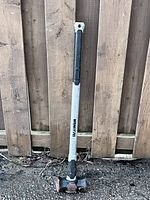 Full view of sledge hammer leaning against fence