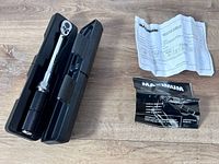 Torque wrench inside open black case with manuals beside