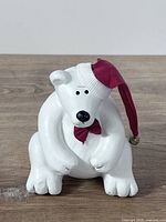 Front view of painted wooden polar bear wearing red Santa hat and bow tie