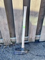 Full view of splitting maul leaning against fence
